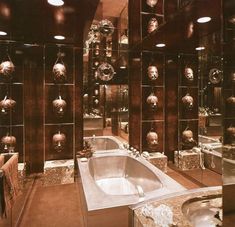 a fancy bathroom with mirrored walls and an oval bathtub in the center, surrounded by glass cubes