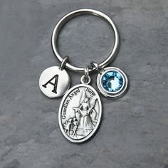 a keychain with an angel and a blue crystal stone on the bottom is shown