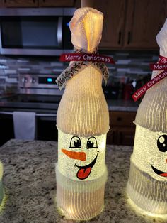 two plastic bottles decorated like snowmen with faces on them, sitting on a kitchen counter