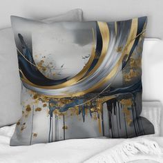 a white bed topped with two pillows covered in black and gold art pieces on top of it