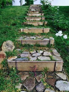 stone steps leading up to a house in the grass with flowers growing on each step