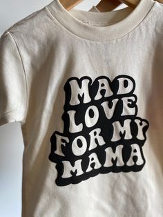 Mad Love for My Mama Tee Have a little who has mad love for their mama? This is the perfect tee for them! Not only great for Valentine's Day but can be worn year round! Bella Canvas unisex tee, natural color. 100% combed and wingspan cotton. Raised lettering. Offered in sizes 2T-5T Please allow 5-7 days max for production* Mama Graphic Tees, Cotton Graphic Tee With Lettering, Funny Cotton T-shirt With Lettering, Mother's Day Cotton Slogan Tops, Playful Organic Cotton Tops With Graphic Print, Playful Mother's Day Tops With Funny Print, Playful Tops With Funny Print For Mother's Day, Mother's Day Graphic Tee With Text Print, Mother's Day Cotton Tops With Lettering