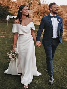 a bride and groom walking in the grass