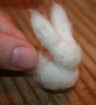 a hand holding a small white object on top of a wooden table