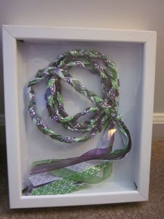 a white box with a purple and green lanyard in the center, on carpeted floor