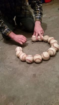 a man kneeling down next to a bunch of baseballs on the ground with their hands