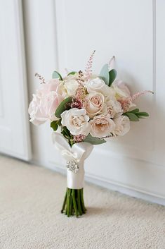 a bridal bouquet with pink and white flowers on the floor next to a door