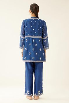 Blue short kurta with silk thread embroidery in floral pattern and round neckline. Paired with straight pant.
Components: 2
Pattern: Embroidery
Type Of Work: Thread, floral
Neckline: Round
Sleeve Type: Three quarter
Fabric: Silk Chanderi
Color: Blue
Other Details: 
Lined
Embroidery on pant hem
Elasticated waist at the back
Side pockets
Closure: Pant: Drawstring
Occasion: Work - Aza Fashions Blue Chikankari Embroidery Sharara For Spring, Blue Sharara With Chikankari Embroidery For Spring, Spring Blue Sharara With Chikankari Embroidery, Blue Chikankari Embroidered Sharara For Spring, Indigo Chikankari Embroidery Sets For Navratri, Indigo Chikankari Sets For Navratri, Indigo Embroidered Sets For Navratri, Fitted Blue Pant Set With Resham Embroidery, Festive Blue Embroidered Pant Set