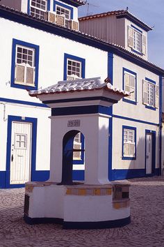 a white and blue building with a bell tower in front of it on a cobblestone street