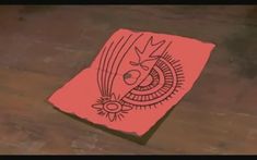 a red piece of paper with an image of a bird on it sitting on top of a wooden table