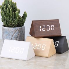 three wooden clocks sitting on top of a table next to a cactus in a pot