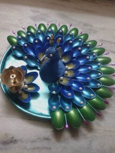 a blue and green peacock on a plate with some gold buttons in its beaks