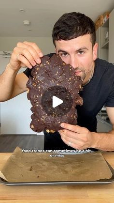 a man holding up a chocolate doughnut in front of his face