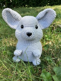 a crocheted mouse sitting in the grass with it's ears folded back