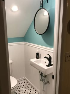 a white sink sitting under a mirror in a bathroom next to a wall mounted faucet