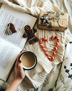 a person is reading a book and holding a cup of coffee