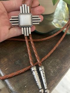 This awesome bolo tie has a southwestern cross design and agate stone centerpiece. Our bolos pair nicely with many of our belt buckles! They make wonderful gifts. The western bolo tie rope length is 100cm (39") and the pendant is 1 3/4'' wide Bohemian Concho Bolo Ties For Rodeo, Adjustable Concho Bolo Ties For Ranch, Western Bolo Ties With Adjustable Length, Bohemian Bolo Tie With Concho, Artisan Adjustable Cross Jewelry, Western Brown Bolo Ties With Concho, Southwestern Bolo Ties With Concho, Western Brown Bolo Tie With Concho, Southwestern Lariat Bolo Ties For Ranch