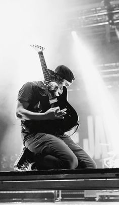 a black and white photo of a man playing an electric guitar