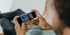 a person sitting on a chair holding a cell phone in their hand and looking at the screen