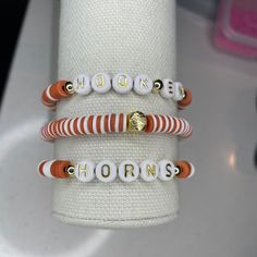 Burnt Orange and White beaded bracelets are fun and fashionable bracelets to show off on any game day! PRODUCT DETAILS:  - All letters are upper case - Bracelets are made with sturdy quality jewelry elastic.  CARING TIPS: - Care should be used to avoid unnecessary over-stretching. Be gentle when placing on and off. - Do not expose your bracelets to water or leave out in direct sunlight.  - Remove bracelets when sleeping, swimming and taking a shower or bath. Please message me with any questions! School Spirit Beaded Bracelet With Letter Beads As Gift, School Spirit Beaded Bracelets With Letter Beads For Gifts, Adjustable White Friendship Bracelets For Game Day, School Spirit Beaded Bracelets, School Spirit Letter Beads Bracelets Gift, Adjustable Beaded Bracelets For Game Day With School Spirit, Orange Letter Beads Bracelet, White Adjustable Name Bracelet For Game Day, Team-colored Sports Bracelets With Letter Beads