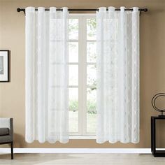 white curtains hanging on the side of a window in front of a chair and table