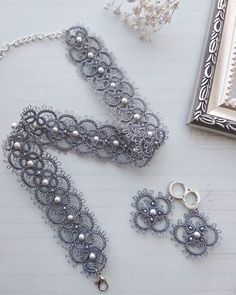 the necklace and earring are next to an ornate frame on a white tablecloth