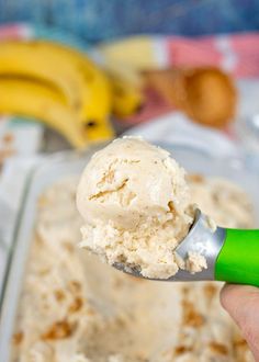 a hand holding a spoon full of ice cream with bananas in the backgroud