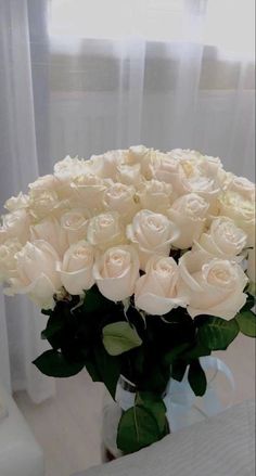 a vase filled with white roses on top of a table