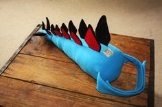 a blue stuffed animal with black and red spikes on it's head sitting on top of a wooden table