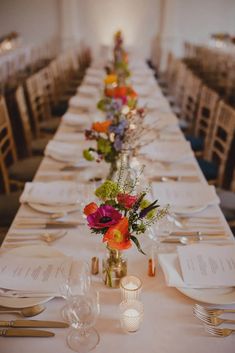 a long table is set with flowers and silverware