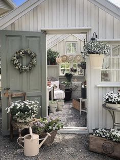 an open door to a white house with potted plants on the outside and inside