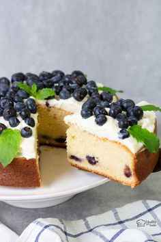 a cake with blueberries and mint on top is cut into two pieces to show the inside