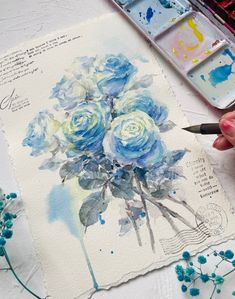 someone is painting flowers on paper with watercolors