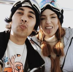 a man and woman taking a selfie in the back of a car with their tongue out