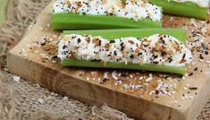 three celery stalks on a cutting board topped with cottage cheese and sprinkles