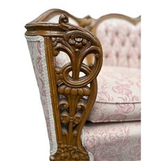 an ornately carved wooden chair with pink and white upholstered fabric