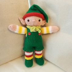 a small knitted elf doll sitting on a couch