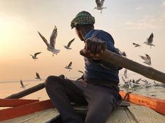 a man on a boat surrounded by seagulls