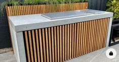 an outdoor bar made out of concrete and wooden slats with plants growing on top