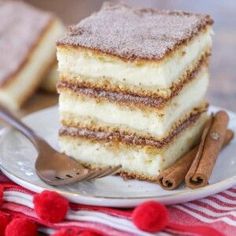 a piece of cake sitting on top of a plate next to a fork and cinnamon sticks