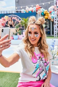 a woman with face paint taking a selfie in front of an amusement park ride