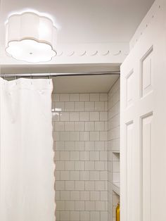 a small bathroom with white tile walls and flooring, along with a shower curtain