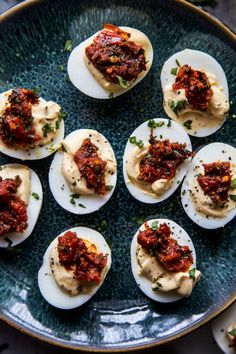 deviled eggs topped with sauce and parsley on a blue plate, ready to be eaten