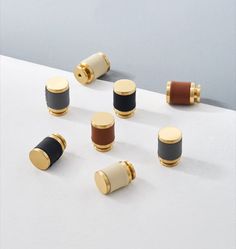 six spools of thread on top of a white surface with gold and black trim