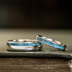 two wedding rings sitting on top of an open book with blue stone inlays