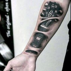 a man with a guitar tattoo on his arm and hand is holding an electronic device