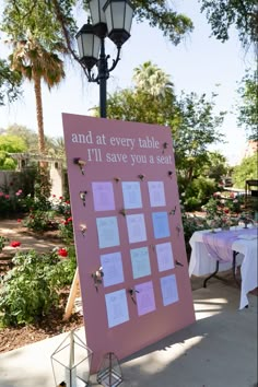 a sign with notes attached to it in front of a light pole and table cloth covered tables