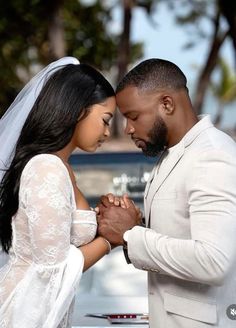 a man and woman standing next to each other in front of a car holding hands