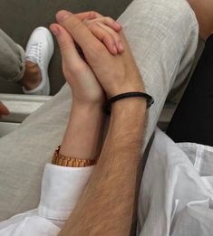 two people holding hands while sitting on a couch