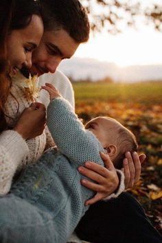 a man and woman holding a baby in their lap while they look at each other